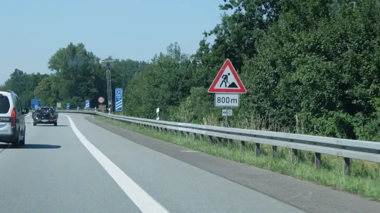 Ein gelbes Warnschild weist auf kommende Bauarbeiten auf der Autobahn hin.