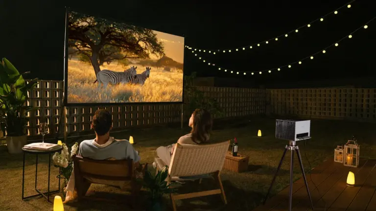Ein Paar genießt abends einen Film bei einem entspannten Open-Air-Kino im Garten.