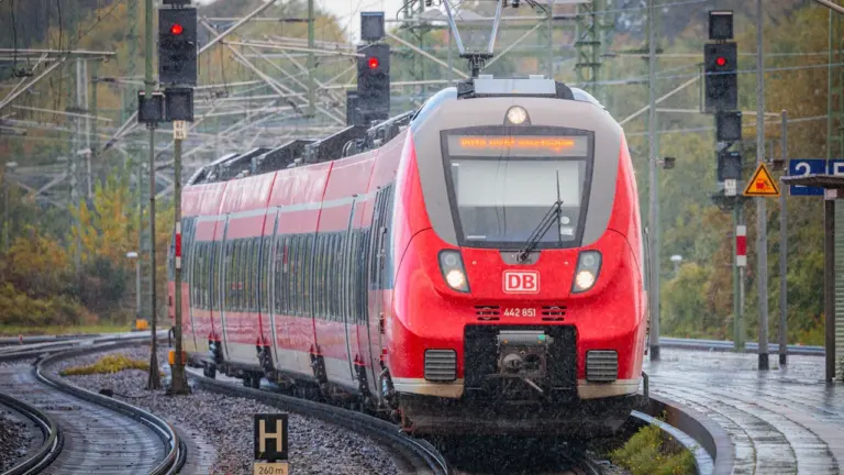 Ein roter Regionalzug der Deutschen Bahn fährt in einen Bahnhof ein.