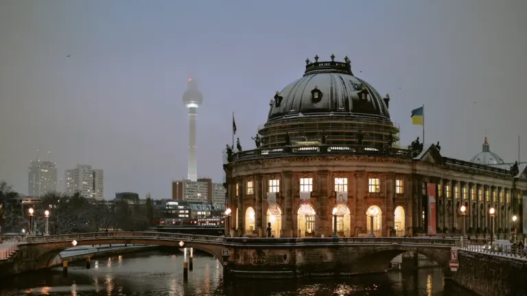 Wehende deutsche Flagge vor dem Berliner Reichstagsgebäude bei klarem blauem Himmel.