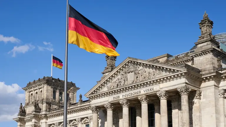 Die deutsche Flagge weht vor dem Reichstagsgebäude in Berlin bei Tageslicht.