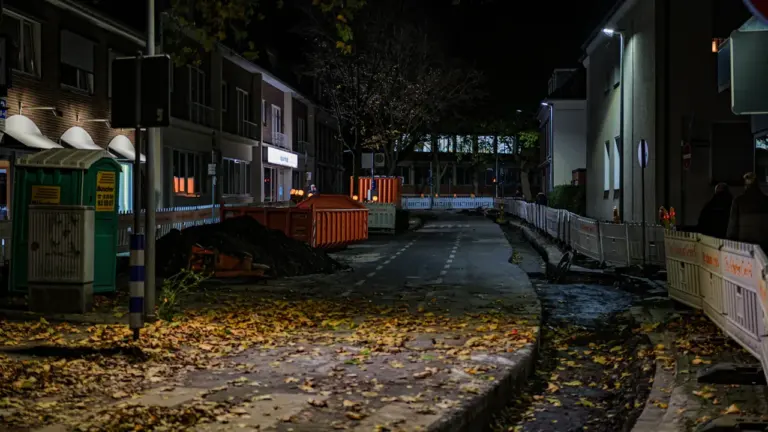 Baustelle in einer nächtlichen deutschen Straße mit abgesperrtem Bereich und Baustellenfahrzeugen.