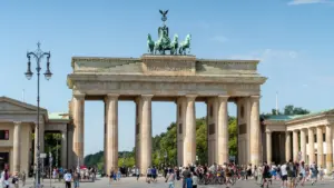 Das Brandenburger Tor in Berlin an einem sonnigen Tag unter blauem Himmel.