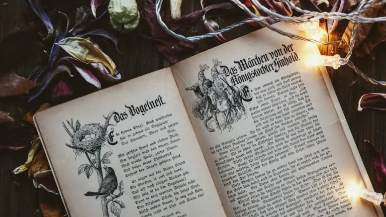 Ein aufgeschlagenes altes Märchenbuch mit Illustrationen, umgeben von Lichterketten und herbstlichen Blättern.