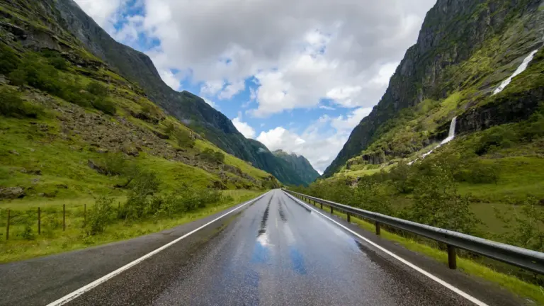 Eine nasse norwegische Bergstraße bei bedecktem Himmel und typischem nordeuropäischen Wetter.