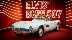 Elvis Presleys berühmter weißer BMW 507 als Ausstellungsstück auf einer roten Plattform.