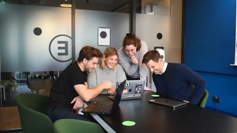 Büro-Team arbeitet gemeinsam an Laptops in einem modernen, hellen Hamburger Bürogebäude.