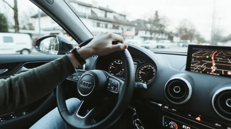 Blick aus der Fahrerperspektive auf das Lenkrad eines modernen Autos im Stadtverkehr