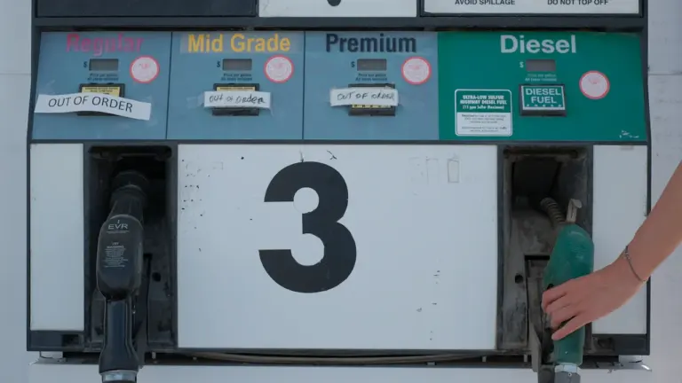 Eine weiß-grüne Zapfsäule an einer Tankstelle in München bei Tageslicht.