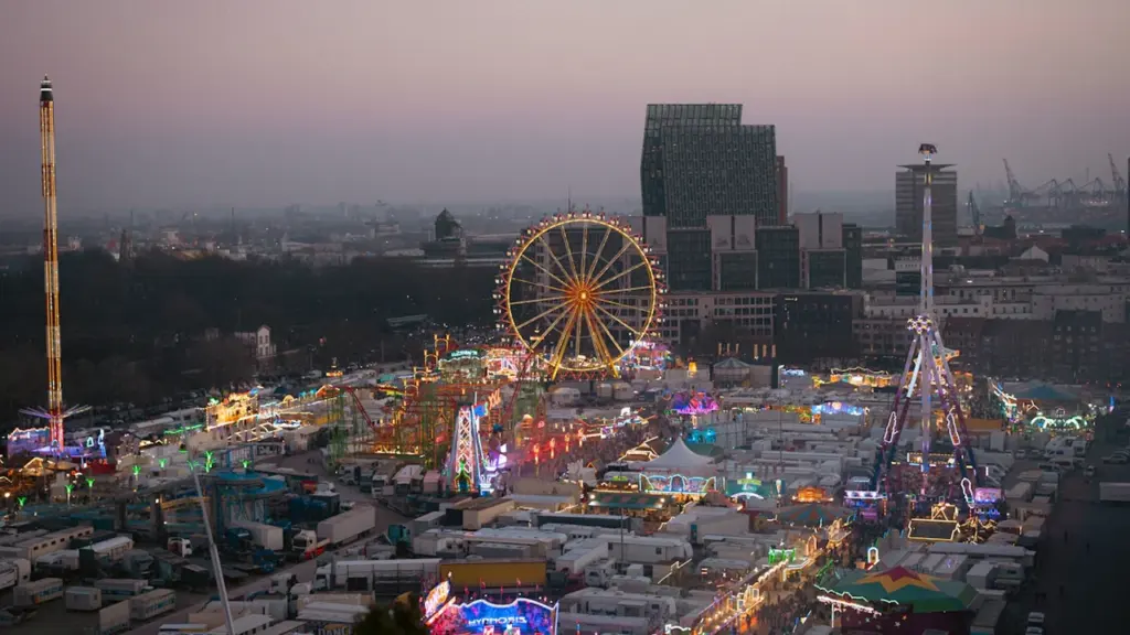 Weitläufige nächtliche Ansicht des Hamburger Doms mit beleuchtetem Riesenrad und Fahrgeschäften.
