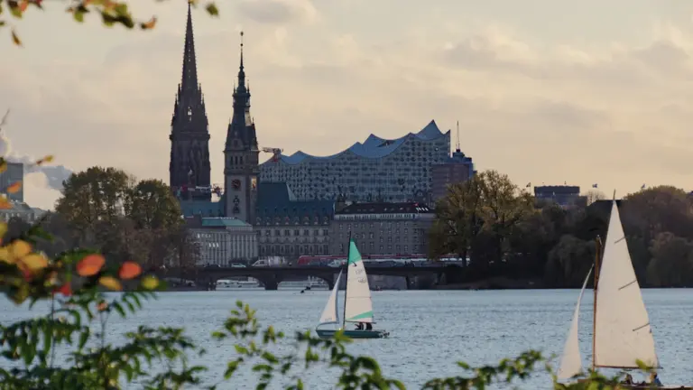 Hamburger Stadtansicht mit Segelboot auf der Alster an einem sonnigen Herbstnachmittag
