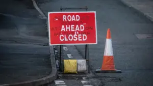 Ein rot-weißes Straßenschild mit der Aufschrift Road Closed und ein orangefarbener Verkehrskegel.