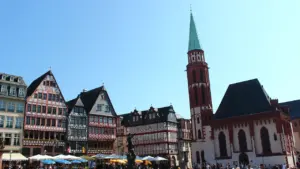 Menschen besuchen den historischen Frankfurter Römerberg bei sonnigem Wetter im Sommer.