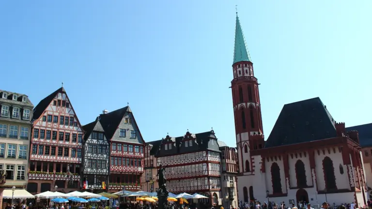Menschen besuchen den historischen Frankfurter Römerberg bei sonnigem Wetter im Sommer.