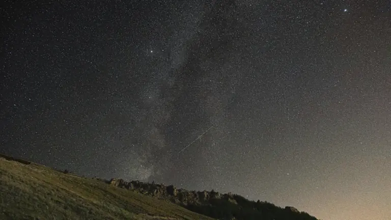 Sternenhimmel über einer grünen Hügellandschaft bei Nacht, ideal für die Beobachtung der Perseiden.