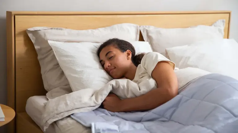Eine junge Frau schläft friedlich in einem hellen, gemütlichen Bett mit weißer Bettwäsche.