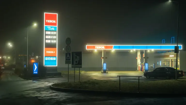 Beleuchtete Tankstelle in der Nacht bei nebligem Wetter mit gut sichtbaren Preistafeln.