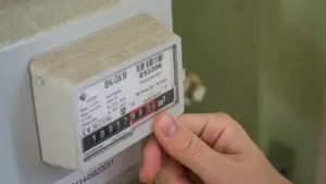 Eine Hand prüft einen modernen Stromzähler zur Überwachung des Energieverbrauchs im Haushalt.