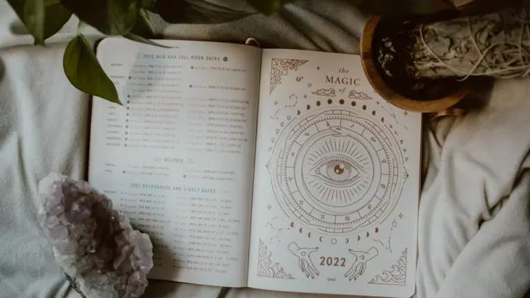 Ein offenes Buch mit astrologischen Symbolen liegt gemütlich auf einer weichen Decke.