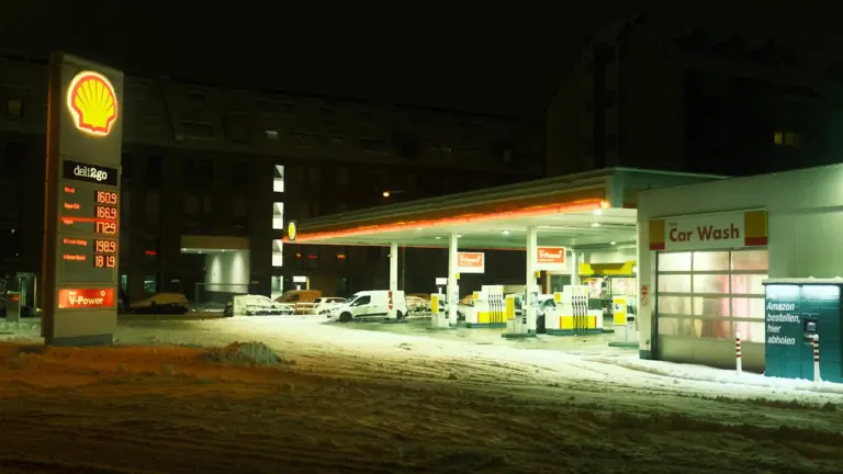 Eine beleuchtete Tankstelle bei Nacht mit Schnee auf dem Boden in Deutschland.