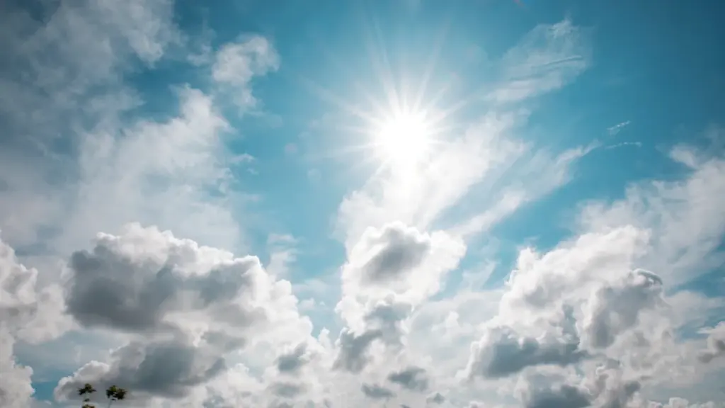 Strahlend blauer Himmel mit weißen Wolken und intensiver Sonneneinstrahlung an einem Sommertag.
