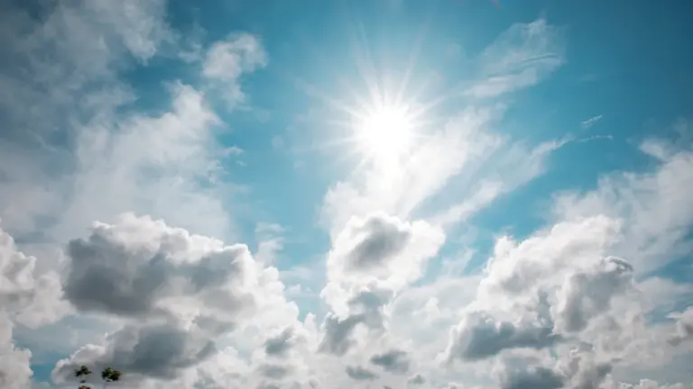 Strahlend blauer Himmel mit weißen Wolken und intensiver Sonneneinstrahlung an einem Sommertag.
