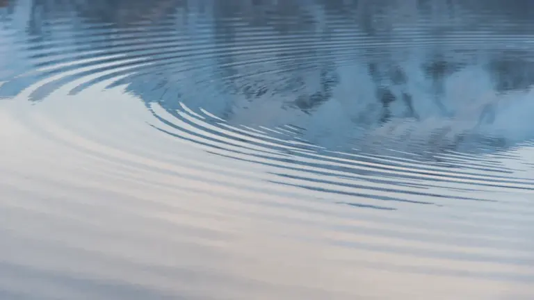 Zeitlupenaufnahme von sanften Wellen auf einer ruhigen Wasseroberfläche bei blauem Licht