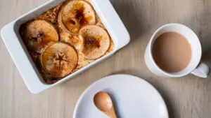 Ein ofenfrischer Apfel-Hafer-Auflauf in einer weißen Keramikform mit einer Tasse Kaffee.