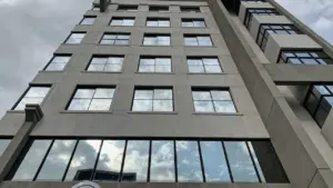 Froschperspektive eines grauen Bürogebäudes unter einem bewölkten Himmel in Deutschland.