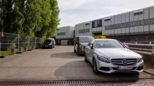Silberner Mercedes vor der Messehalle 8.2 auf dem Berliner Messegelände unter bewölktem Himmel.