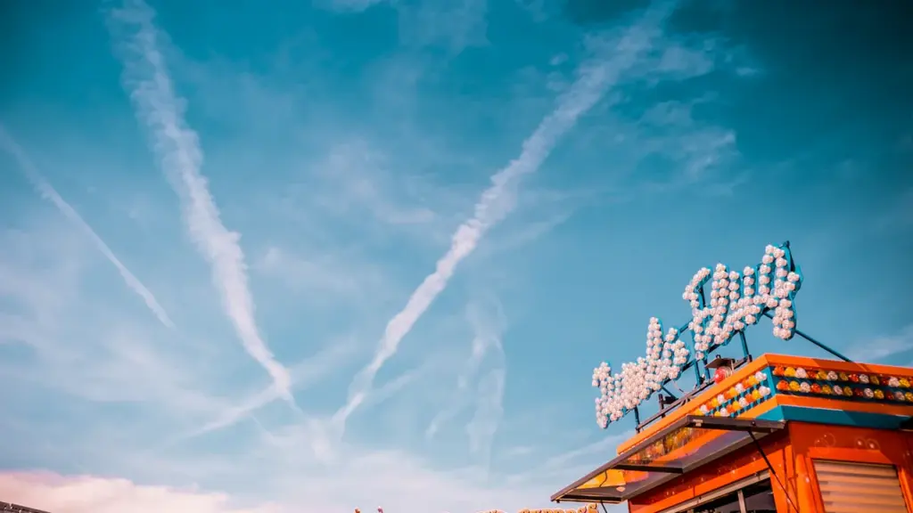 Buntes Volksfest auf der Theresienwiese mit Fahrgeschäften unter einem strahlend blauen Himmel.