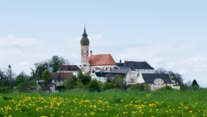 Historische Kloster Andechs Kirche auf einem grünen Hügel mit Frühlingswiese in Bayern.