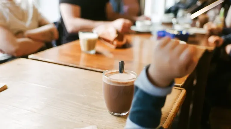 Menschen sitzen an einem hölzernen Tisch in einem gemütlichen Café in Köln.