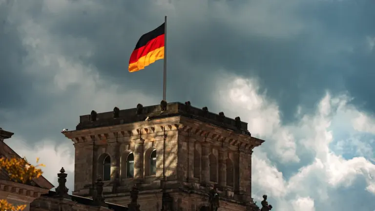 Die deutsche Flagge weht über dem historischen Reichstagsgebäude unter einem bewölkten Himmel.