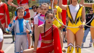 Junge Zirkuskünstler in farbenfrohen Kostümen bereiten sich auf eine festliche Parade vor.