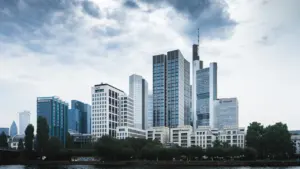 Die monumentale Euro-Skulptur vor der modernen Frankfurter Skyline im Sonnenschein.
