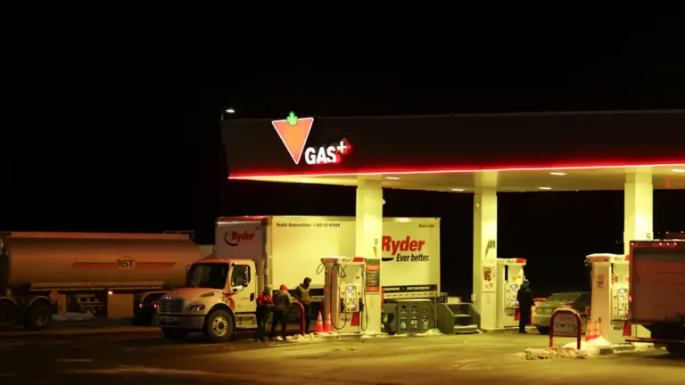 Eine nächtliche Tankstelle mit Lastwagen und Autos während eines Tankvorgangs bei Dunkelheit.