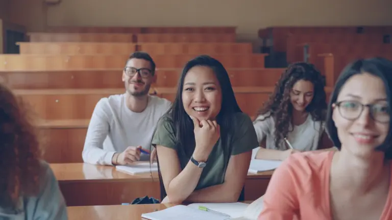 Schüler in einem modernen Hörsaal lächeln motiviert in Richtung der Kamera.