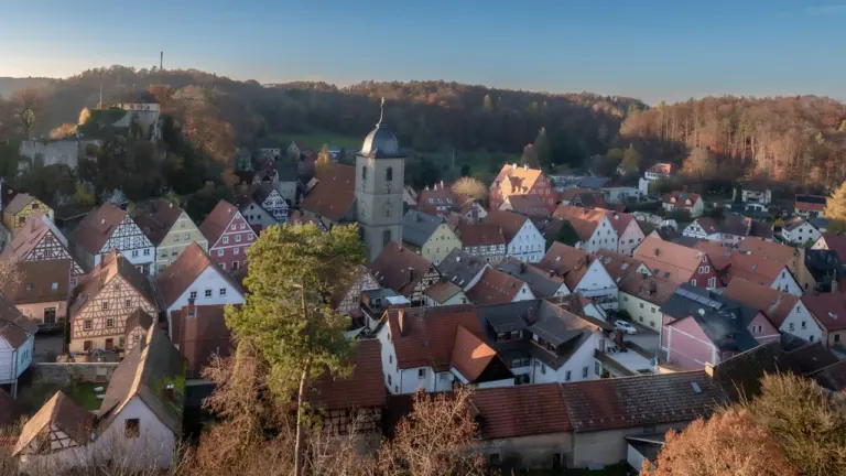 Historische deutsche Stadt mit Kirchturm eingebettet in eine herbstliche Hügellandschaft am Reformationstag.